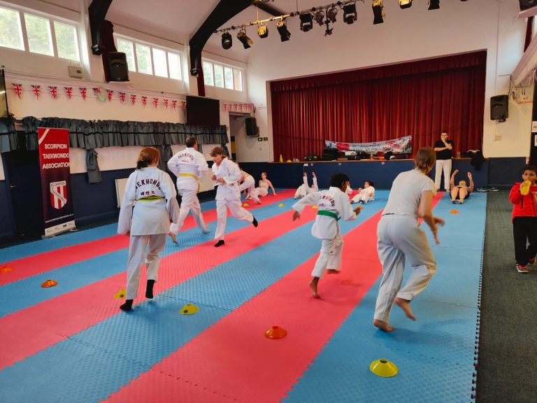 A group of students are playing a warm up game on red and blue mats